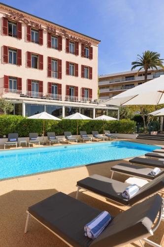 une piscine avec des chaises longues et un hôtel dans l'établissement Best Western Hôtel des Orangers Cannes, à Cannes
