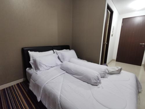 - un lit avec des draps et des oreillers blancs dans l'établissement ARSAKHA 004 Transpark Cibubur By Nigiri Amour, à Kalimanggis