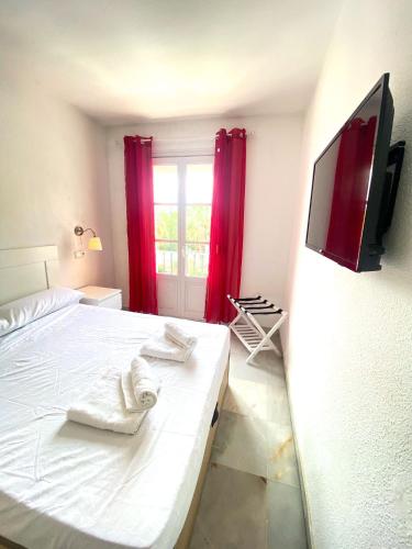 a bedroom with a bed and a tv on a wall at Los Girasoles in Marina Botafoch in Ibiza Town