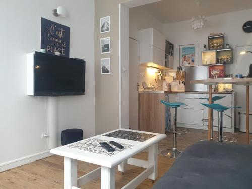 Il comprend un salon avec une table blanche et une cuisine. dans l'établissement L' escale du bord de mer, à Dunkerque