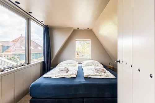 um pequeno quarto com uma cama azul num sótão em Luxury private farmhouse cottage near Amsterdam plus home cinema em Ilpendam