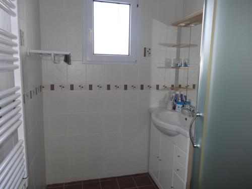 une salle de bain blanche avec un lavabo et une fenêtre dans l'établissement Charmante maison 5 pers, proche plage et centre, avec jardin, BBQ et Wi-Fi, L'Aiguillon-sur-Mer - FR-1-476-42, à LʼAiguillon-sur-Mer