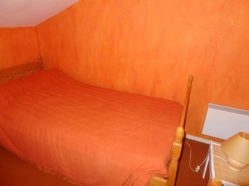 um pequeno quarto com uma cama com lençóis laranja em Maison La Faute-sur-Mer, 2 pièces, 4 personnes - FR-1-476-8 em La Faute-sur-Mer
