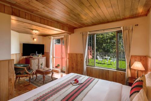 a bedroom with a bed and a large window at Willow Hill by Nature Resorts in Ooty