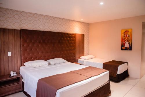 a hotel room with two beds and a headboard at Hotel Village Premium Caruaru in Caruaru