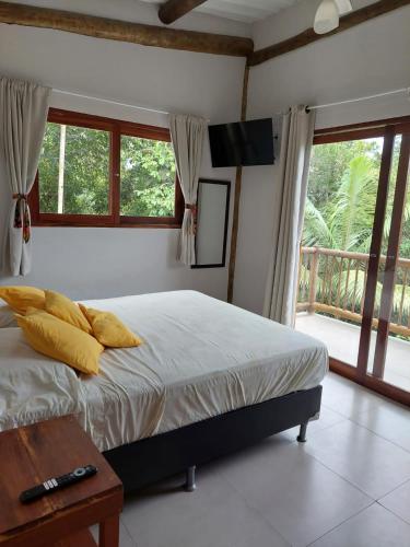 a bedroom with a bed with yellow pillows and a television at Casa da Ponte, Trindade in Trindade