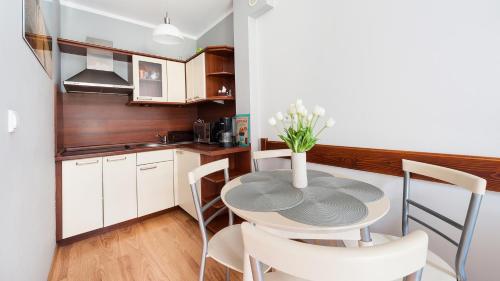 una cocina con una mesa con un jarrón de flores. en Apartamenty Sun & Snow Centrum, en Zakopane