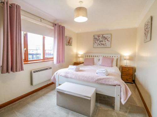 a bedroom with a white bed with pink sheets and a window at Solace Lodge in Norwich