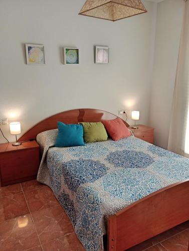 Un dormitorio con una cama con almohadas de colores. en Apartamento playero con vistas a la montaña, en Castell de Ferro