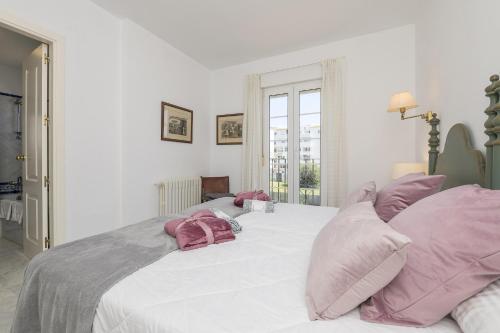 1 dormitorio con 1 cama blanca grande con almohadas rosas en Los Jandalos, en El Puerto de Santa María