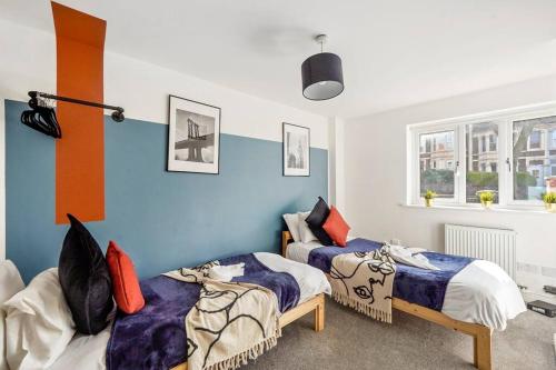 2 Betten in einem Zimmer mit blauen und weißen Wänden in der Unterkunft Lovely Bristol Gem - Sleeps 24 in Bristol