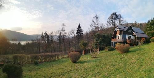 dom na wzgórzu w trawiastym polu w obiekcie Konkelówka- Dom z ogrodem i sauną, Góra Żar i jezioro w Międzybrodziu Żywieckim