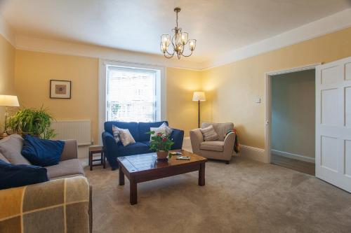 una sala de estar con sofás azules y una mesa. en Drury's, en Corfe Castle