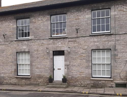 a brick building with a white door and windows at Drury's in Corfe Castle