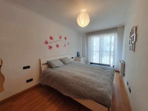 a bedroom with a bed and a tree with pink flowers on the wall at Apartamento Playa Jardín in Ribeira