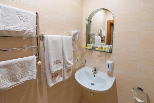 a bathroom with a sink and a mirror and towels at Hotel Kopa - Lviv in Lviv