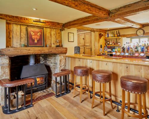 a bar with a stone fireplace and bar stools at Full Moon Inn Rudge in Frome