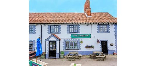 a white building with tables and chairs in front of it at OYO The Billingford Horseshoes in Scole