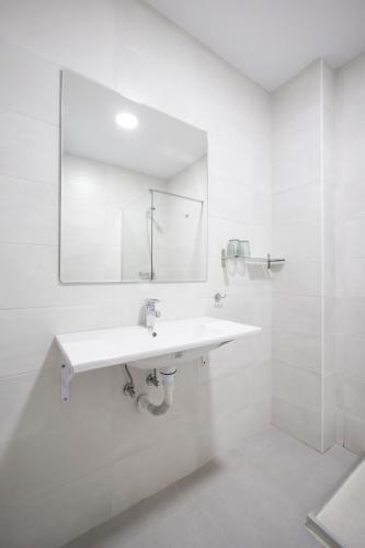 a white bathroom with a sink and a mirror at Hotel Pinar Somo Surf in Somo