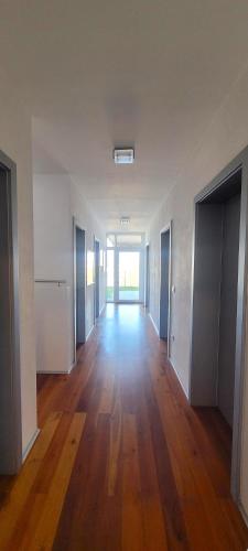 an empty room with a hallway with doors and wood floors at Mountains and Lakes - Villa Gaumberg in Linz