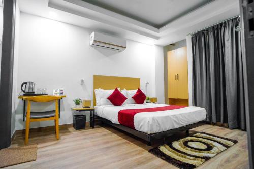 sypialnia z łóżkiem z czerwonymi poduszkami i biurkiem w obiekcie SaltStayz Golf Course Road w mieście Gurgaon