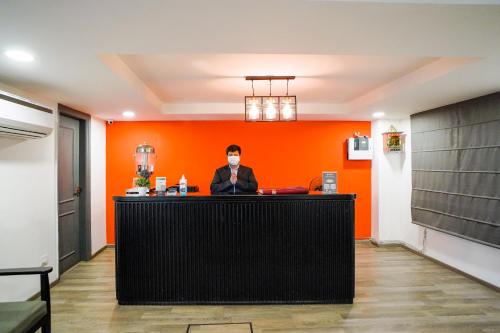 a man wearing a mask behind a counter in an orange room at Saltstayz Express - Golf Course Road & DLF Phase-1 in Gurgaon