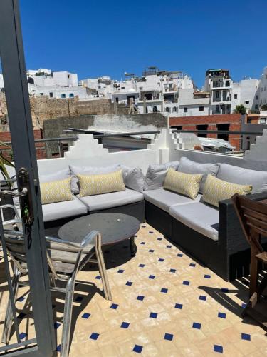 a patio with a couch and a table on a roof at Kasbah’s road Art house in Tangier
