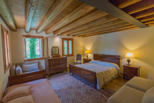 a bedroom with a bed and a chair in a room at Casa sul Fiume County House in Solagna