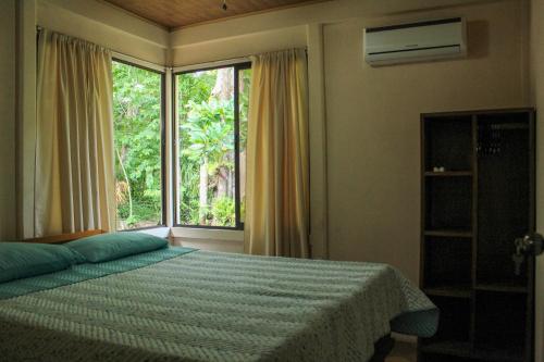 1 dormitorio con cama y ventana grande en Casa a 26 kilómetros de Jaco rodeado de naturaleza, en Jacó