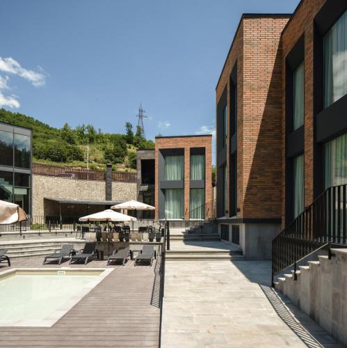 a building with a deck with chairs and umbrellas at Aurora Luxe in Dilijan