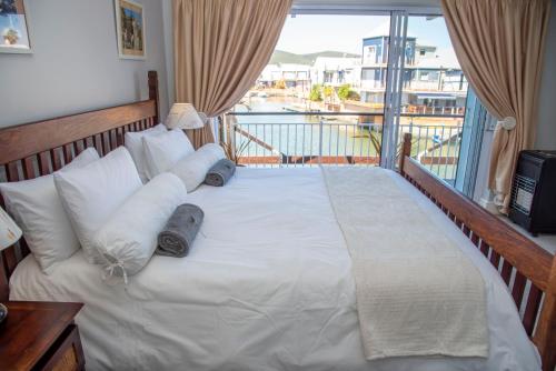 a bed in a room with a balcony at WATERFRONT 2 Bed Home with mooring at Knysna Quays in Knysna