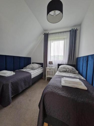 a bedroom with two beds and a window at Tatra Apartments z zewnętrznym jacuzzi in Biały Dunajec