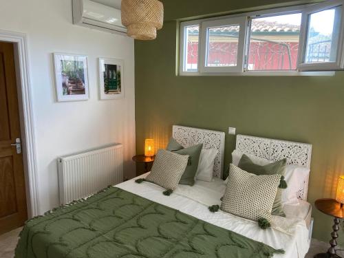 a bedroom with a green bed with two windows at Villa by the Lake in Karoubatika near Agios Ioannis in Agios Ioannis