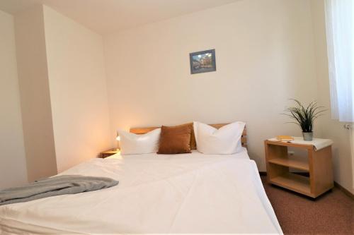 un dormitorio con una cama con sábanas y almohadas blancas en Altes Wasserwerk App 13, en Wustrow