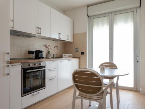 cocina con armarios blancos, mesa y sillas en Franci Loft, en Pescara