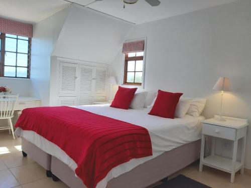 um quarto com uma grande cama branca com almofadas vermelhas em Catch the breeze em Knysna