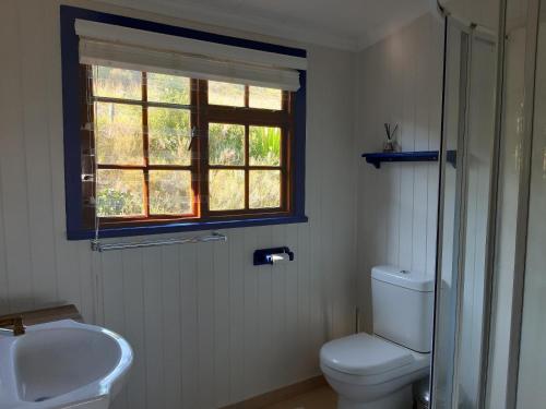 uma casa de banho com um WC, um lavatório e uma janela em Catch the breeze em Knysna