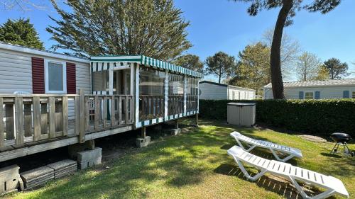 a yard with two white benches and a house at MobilHome 2 chambres 229 dans Camping 4 étoiles in Pont-Aven