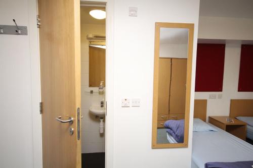 珀斯的住宿－Perth Youth Hostel and Apartments，一间设有镜子、一张床和一个水槽的客房