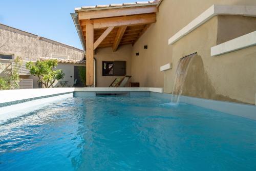 a swimming pool with a waterfall in a house at La Fontaine aux Fées in Lagnes