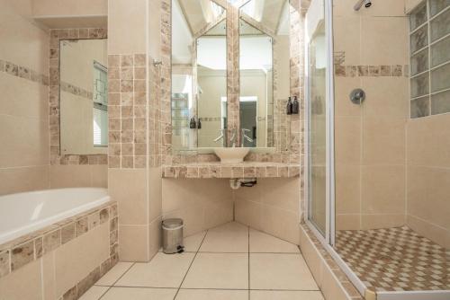 a bathroom with a tub and a sink and a shower at Millard Crescent Guest House in Port Elizabeth
