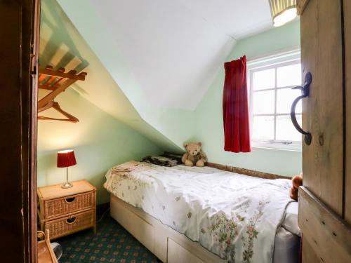 a bedroom with a bed with a teddy bear on it at 1 Forge Cottages in Saxmundham