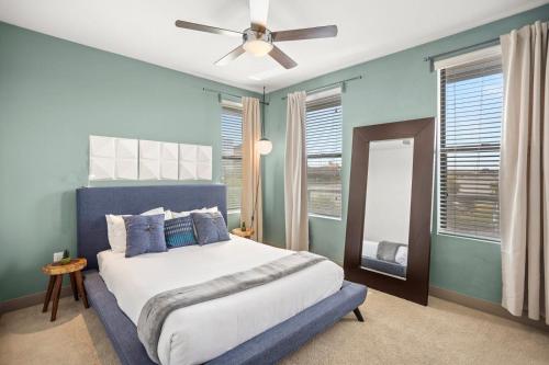 een slaapkamer met een bed met blauwe muren en een plafondventilator bij Modern Town Lake Penthouse by CozySuites in Tempe