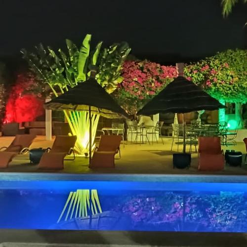 a pool with chairs and umbrellas at night at Riad côté jardin in Saly Portudal