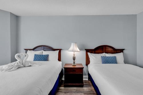 a bedroom with two beds and a table with a lamp at Breathtaking 2BR Condo w Floor-to-Ceiling Windows Overlooking Ocean in Myrtle Beach