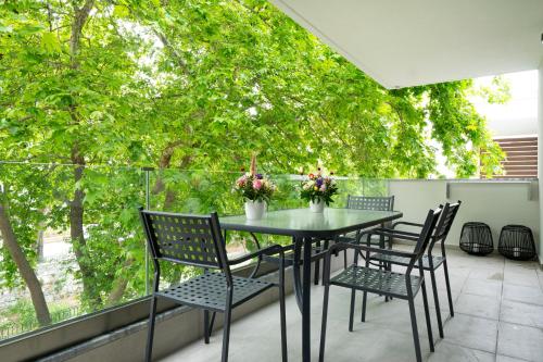 ネア・ペラモスにあるMedusa Luxury Apartmentsの木々のあるバルコニー(テーブル、椅子付)