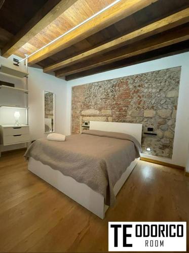 a bedroom with a bed and a stone wall at Teodorico Room & Apartment in Verona