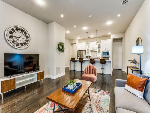 a living room with a large tv and a couch and a table at CozySuites Uptown 3BR King Beds Skyline View in Dallas