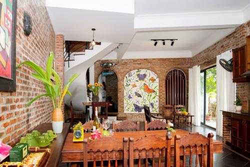 a dining room with a brick wall at Calm House 2 Homestay Hoi An in Hoi An