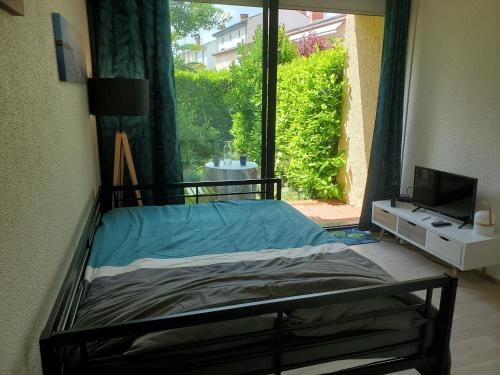 Appartement avec jardin privatif في ألبي: غرفة نوم بسرير ونافذة بها تلفزيون